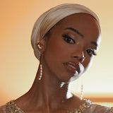 Woman wearing a headscarf and beaded top against a warm-toned background