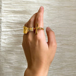 Gold Egyptian Ankh statement ring worn on a hand against a textured background by KIRO UK