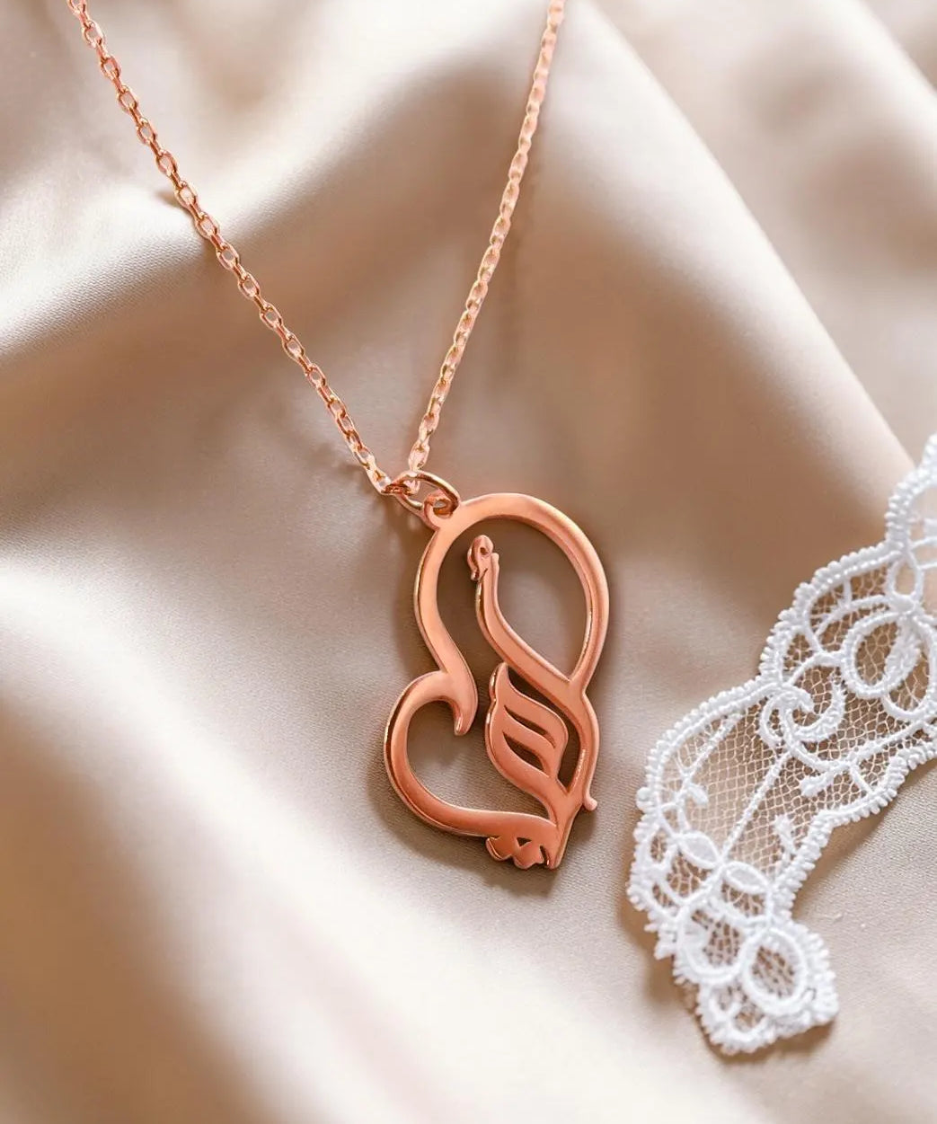 Rose gold plated Arabic calligraphy mother necklace with a decorative heart pendant displayed on soft satin from KIRO UK