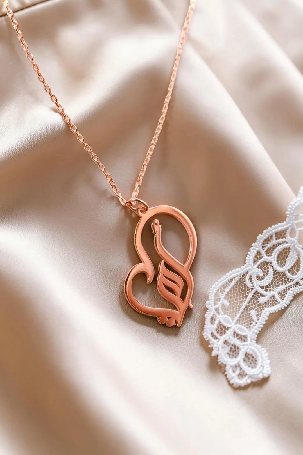 Rose gold plated Arabic calligraphy mother necklace with a decorative heart pendant displayed on soft satin from KIRO UK