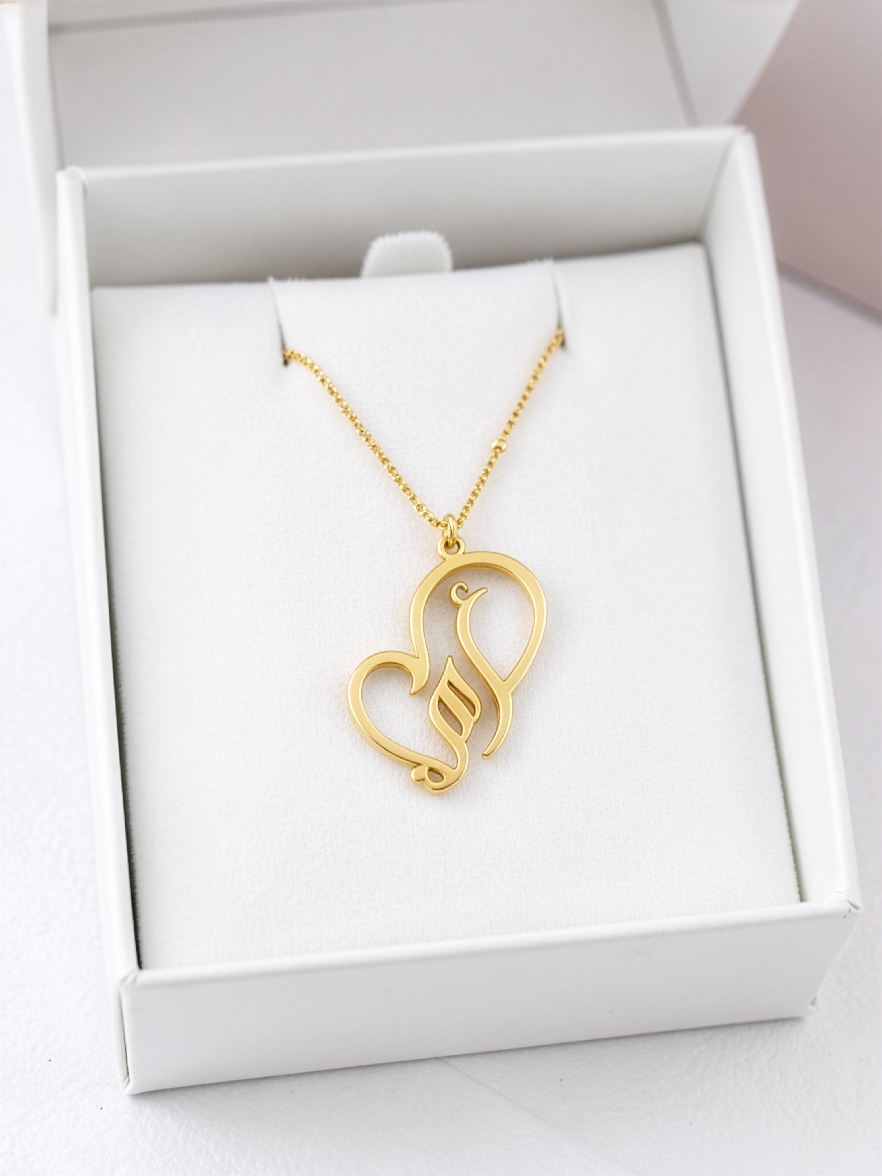 Gold plated necklace featuring Arabic calligraphy for My Mother in a heart shaped pendant displayed in a white jewellery box by KIRO UK