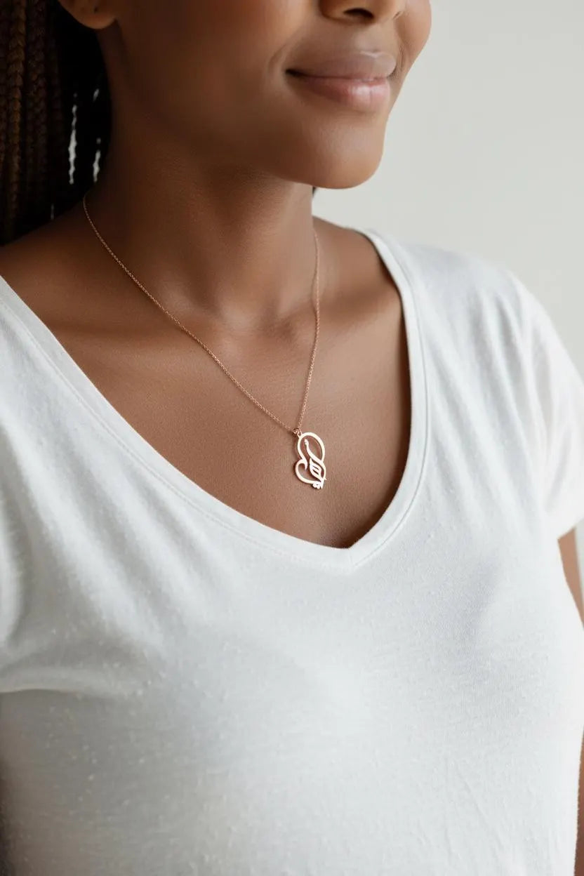 KIRO UK gold plated Arabic calligraphy necklace featuring a My Mother pendant in a decorative heart shape worn on a woman in a white top