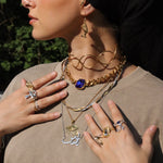 Woman in a black headscarf wearing a gold plated Arabic calligraphy name necklace layered with chains and symbolic pendants