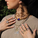 Woman in a black headscarf wearing a gold plated Arabic calligraphy name necklace layered with chains and symbolic pendants