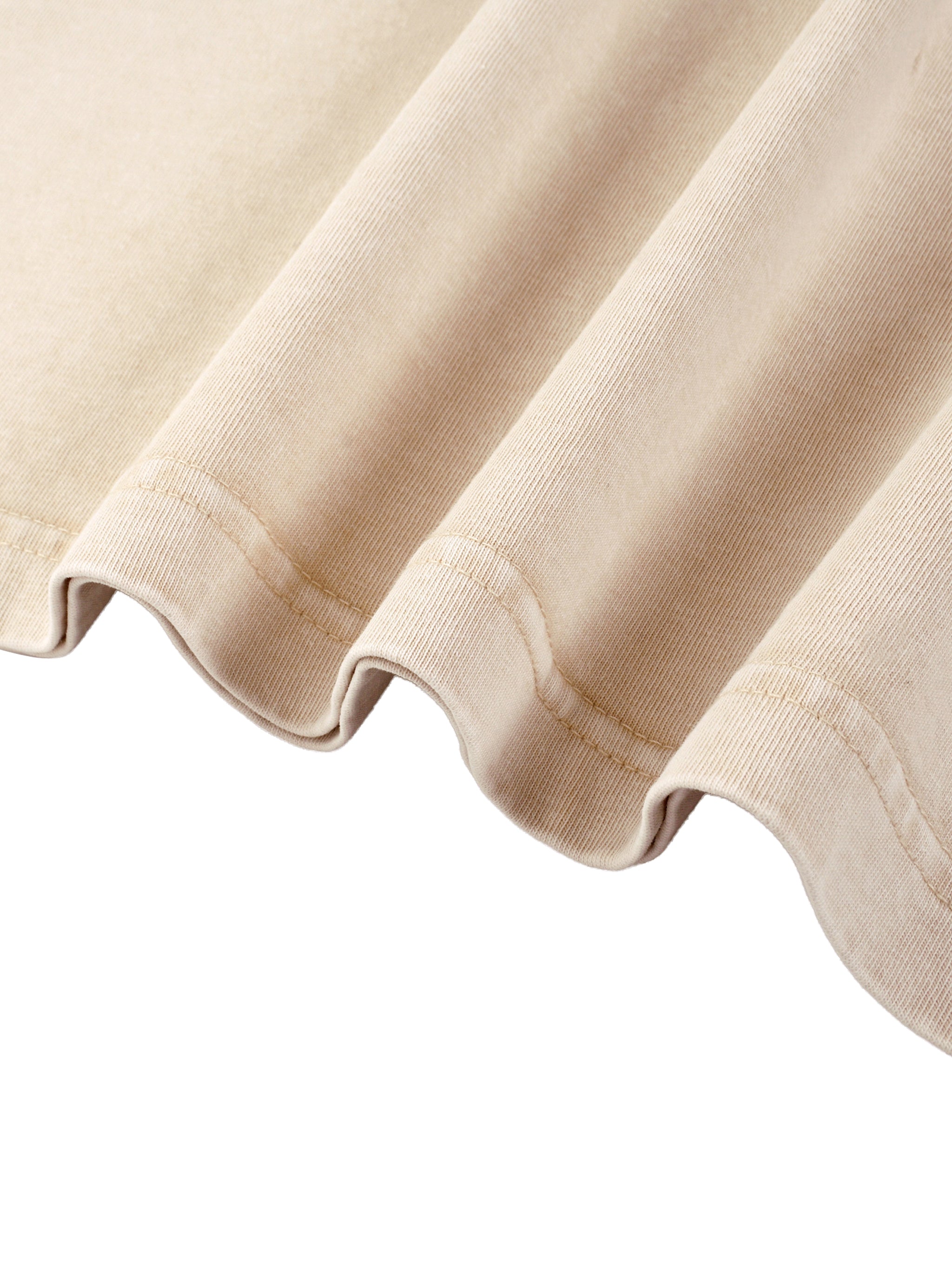 Close up of beige cotton T shirt fabric with a softly curved stitched hem from kiro Clothing