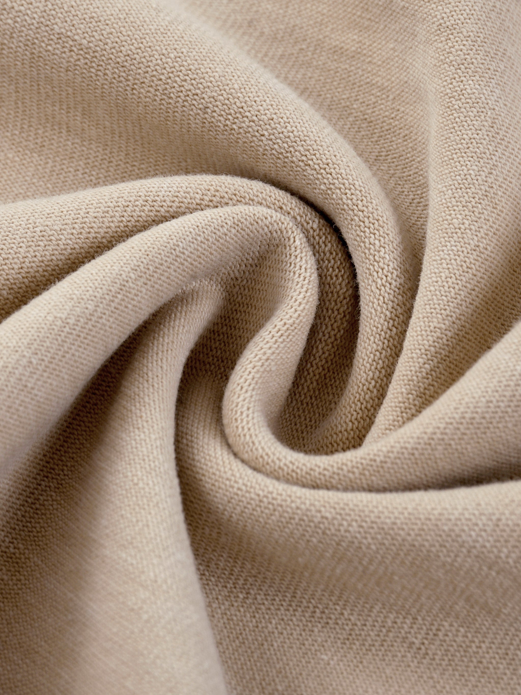 Close up of beige cotton fabric with a soft textured weave and flowing folds from kiro Clothing collection