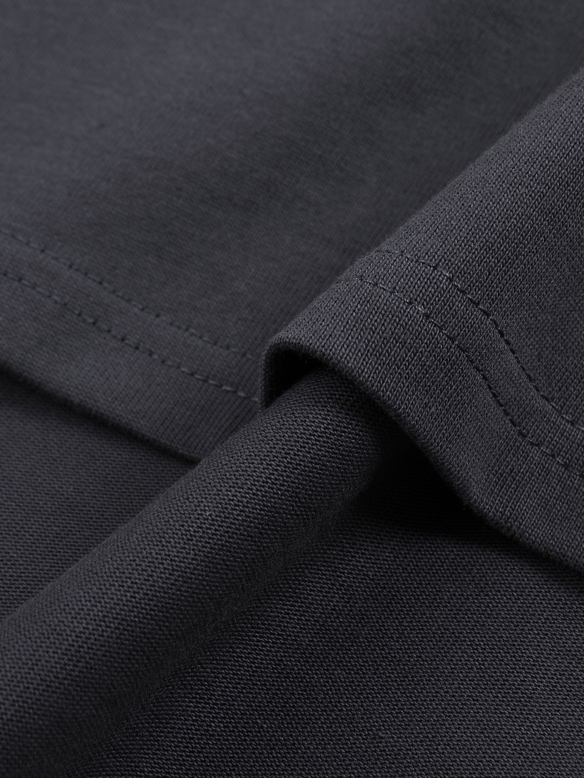 Close up of black cotton fabric and stitched seams on the Masr not Egypt T shirt by KIRO from the Clothing collection