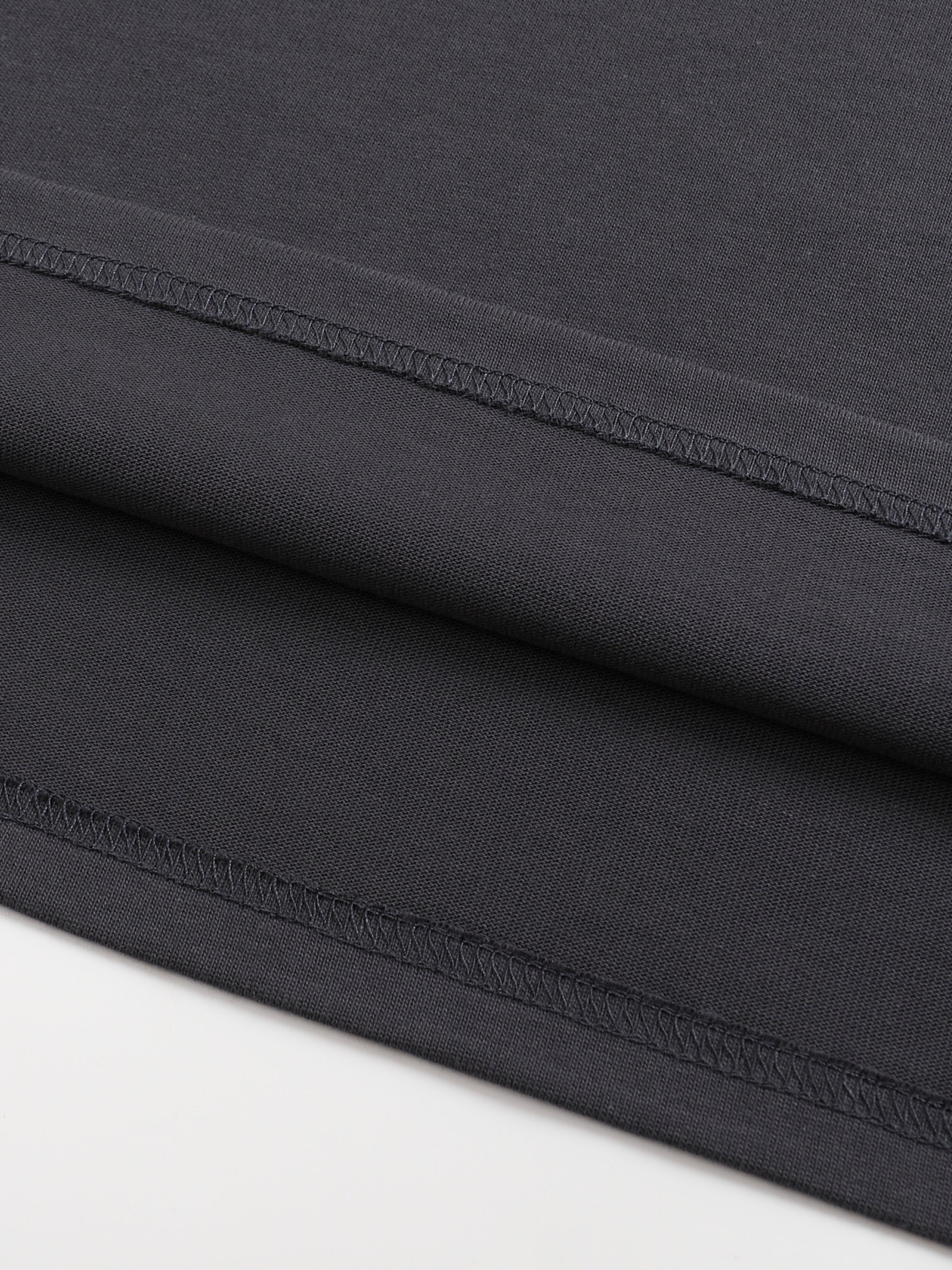 Close up of black cotton garment fabric showing neat stitched seams and soft folded layers from an KIRO Clothing piece