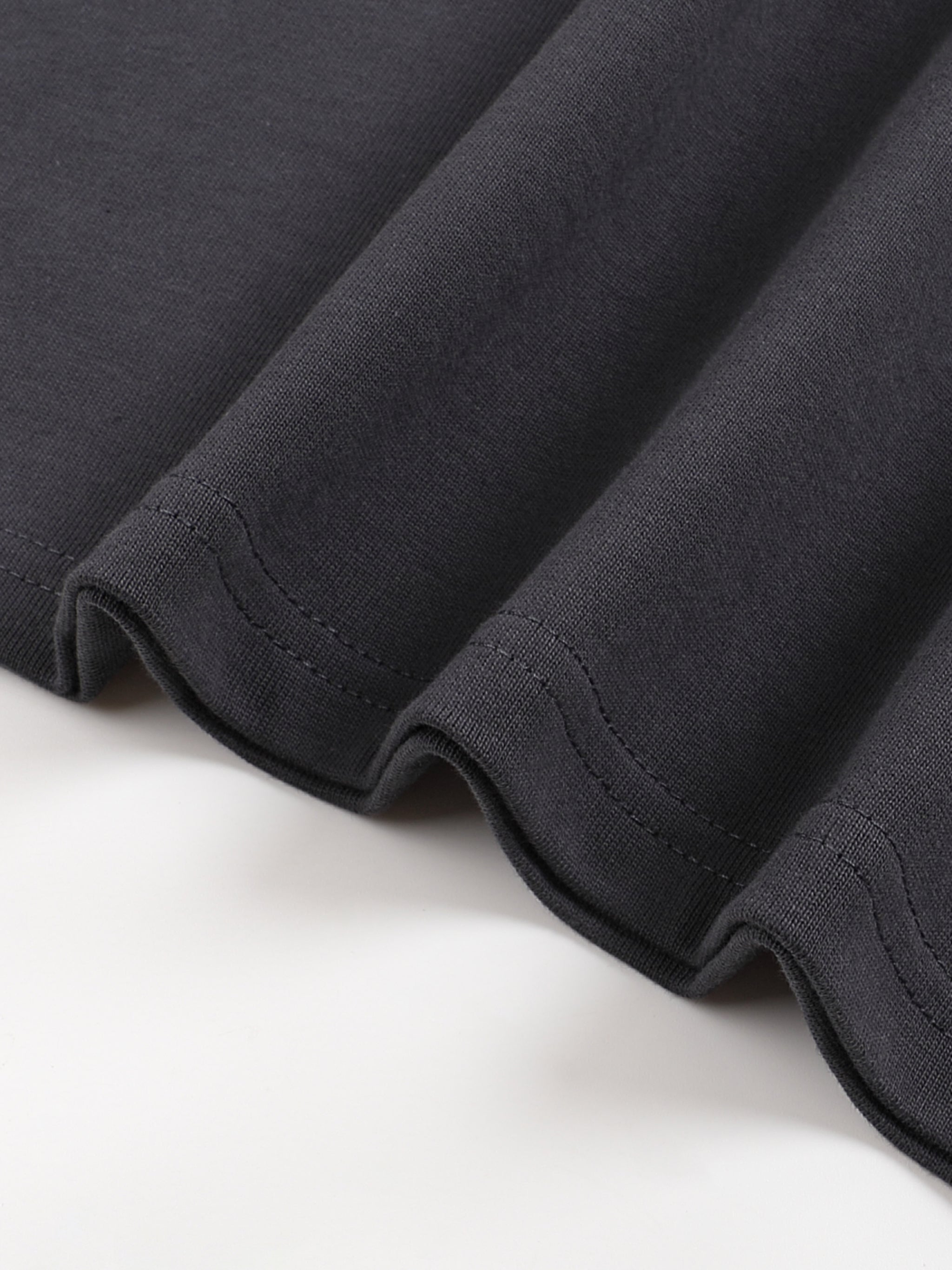 Close up of black cotton T shirt hem with neat double stitching and soft folded fabric detail from KIRO Clothing