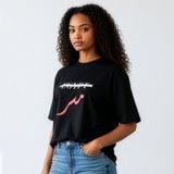 Female model wearing a black oversized cotton shirt with crossed out Egypt text and red Arabic lettering paired with blue jeans from KIRO Clothing