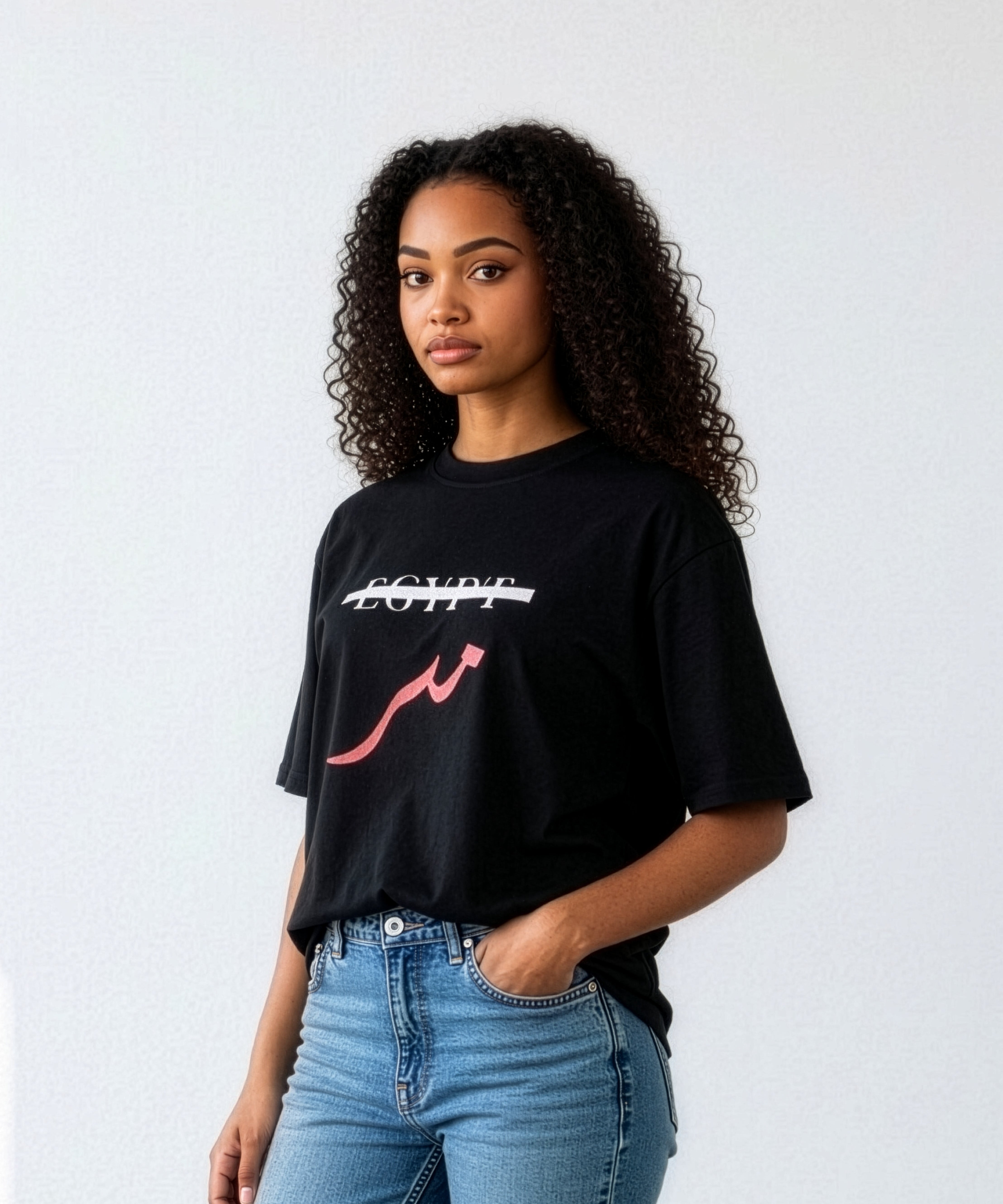 Female model wearing a black oversized cotton shirt with crossed out Egypt text and red Arabic lettering paired with blue jeans from KIRO Clothing