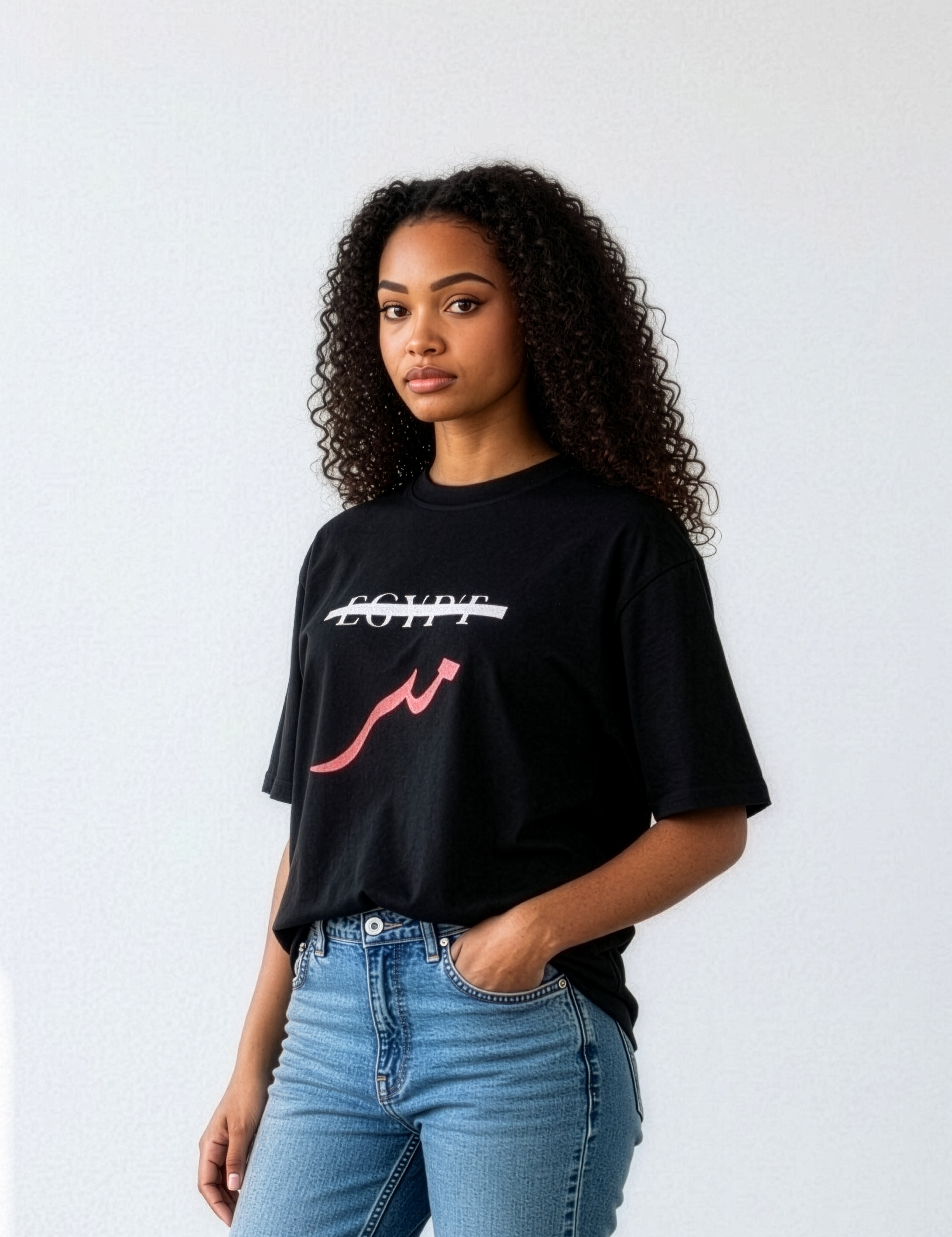 Female model wearing a black oversized cotton shirt with crossed out Egypt text and red Arabic lettering paired with blue jeans from KIRO Clothing