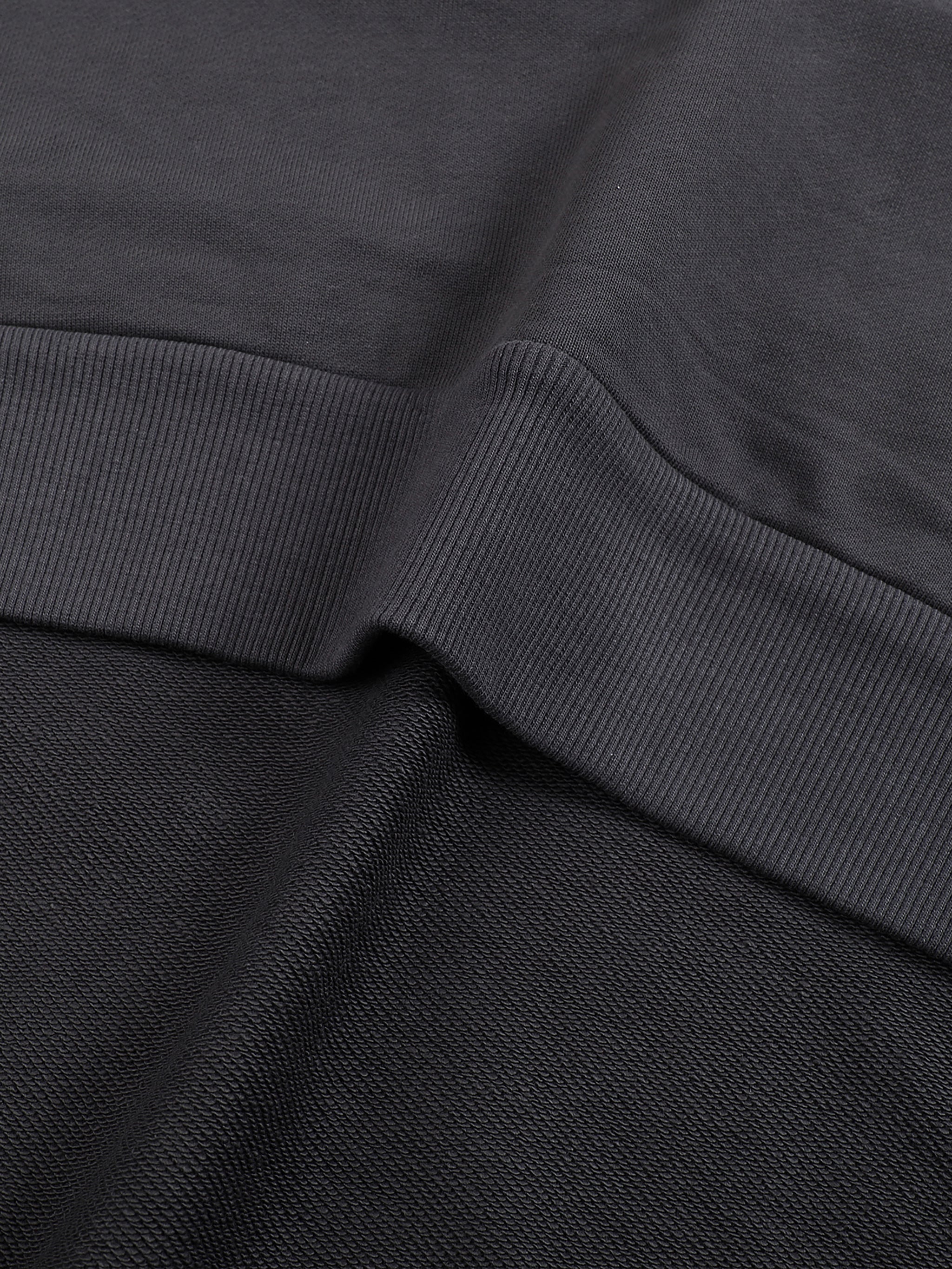 Close-up of black cotton hoodie fabric with a ribbed hem detail from KIRO Clothing