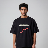 Male model wearing a black oversized cotton T shirt with the word Egypt crossed out and red Masr lettering on the front
