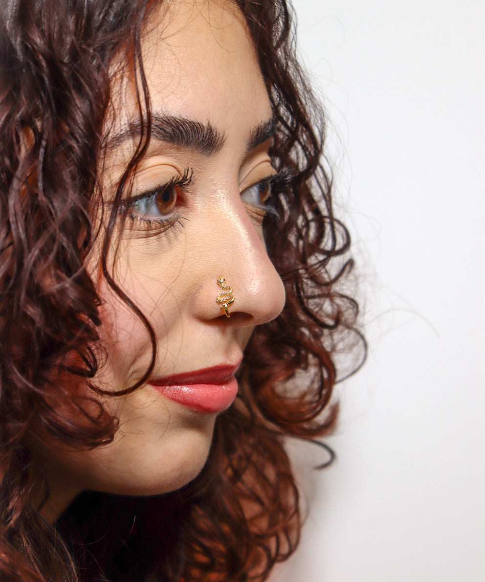 Close-up of a woman wearing a gold serpent faux nose ring, shown on the side of her nose. KIRO UK Nose Ring, Faux nose rings collection