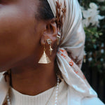 model wearing KIRO 18k Gold Plated Hollow pyramid earrings. They have a hieroglyphic design and pattern on each side.