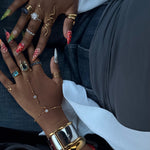 KIRO silver belt bangle with gold buckle detail worn on wrist with multiple layered rings and hand chain jewelry