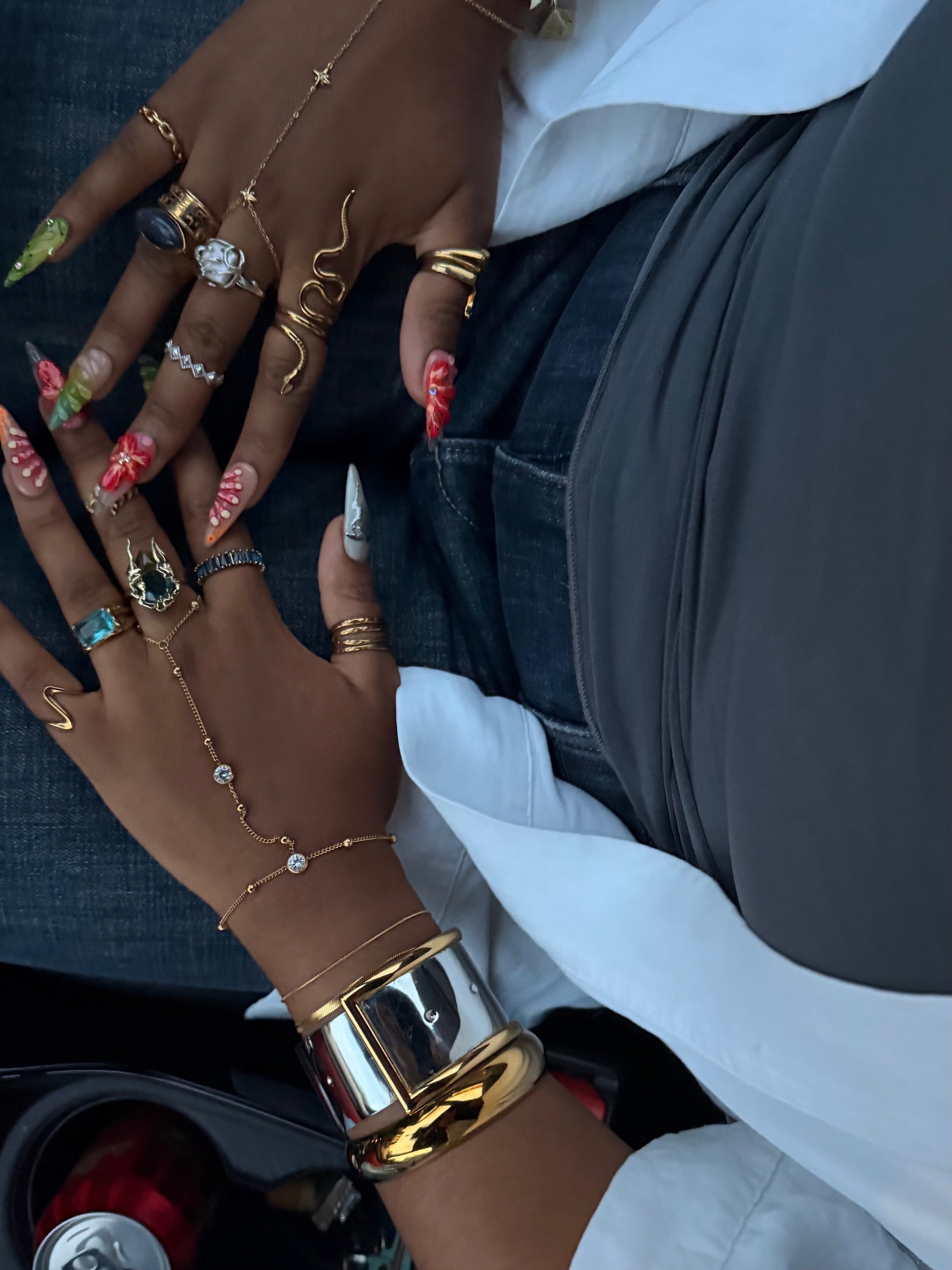 KIRO silver belt bangle with gold buckle detail worn on wrist with multiple layered rings and hand chain jewelry