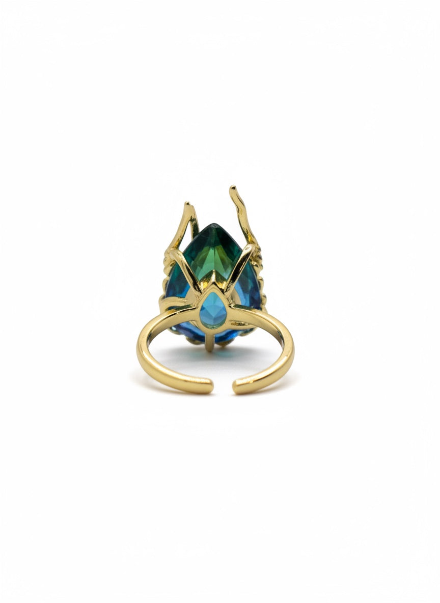 KIRO Amarna ring with a large, faceted blue-green cubic zirconia gemstone set in 18K gold plated metal. Resizeable.
