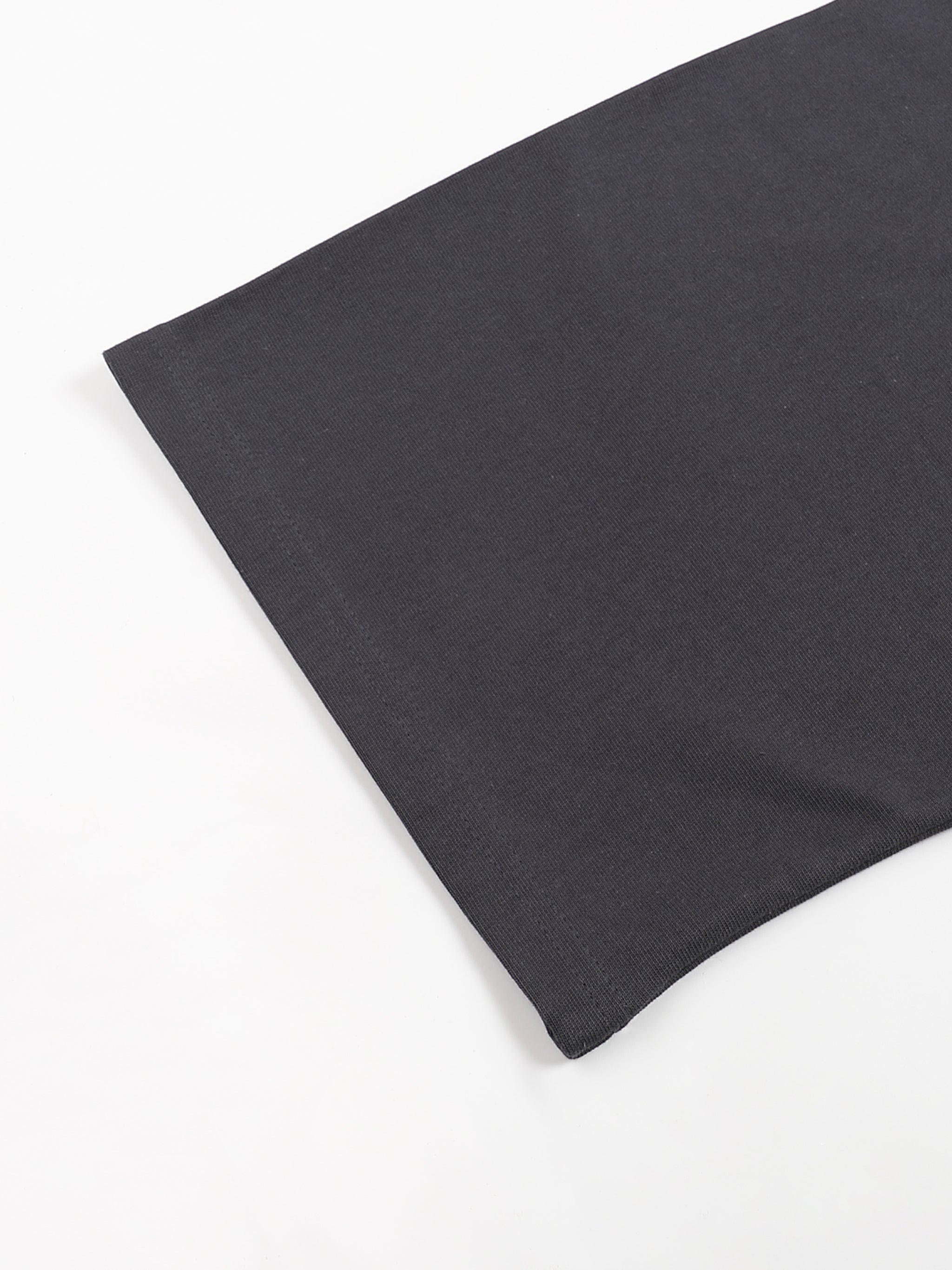 Close up of black cotton fabric from a KIRO Egyptian collage T shirt showing a smooth knit texture and clean hem edge