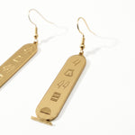 KIRO gold plated stainless steel drop earrings featuring oval cartouche pendants with engraved Egyptian hieroglyphs.