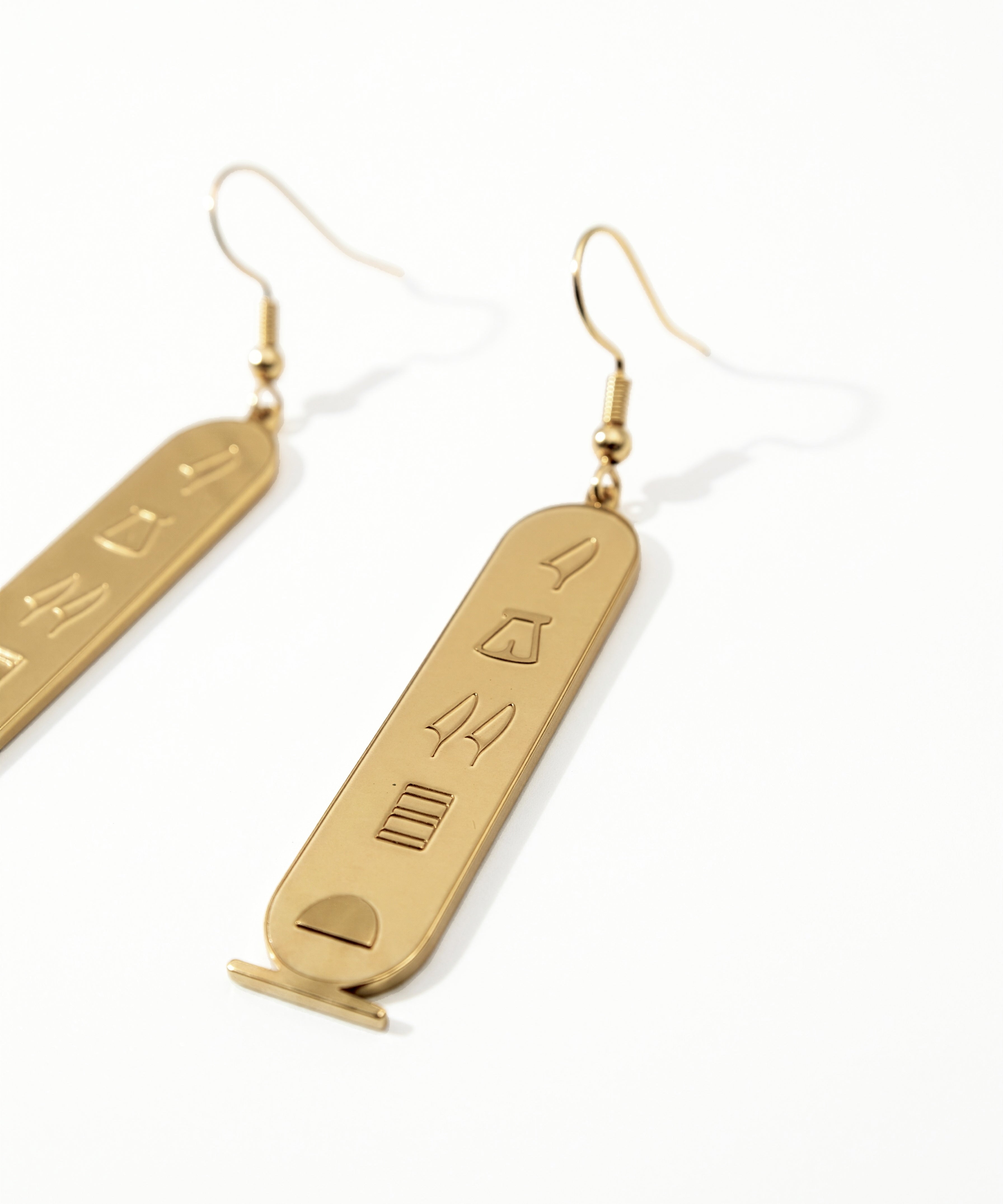 KIRO gold plated stainless steel drop earrings featuring oval cartouche pendants with engraved Egyptian hieroglyphs.