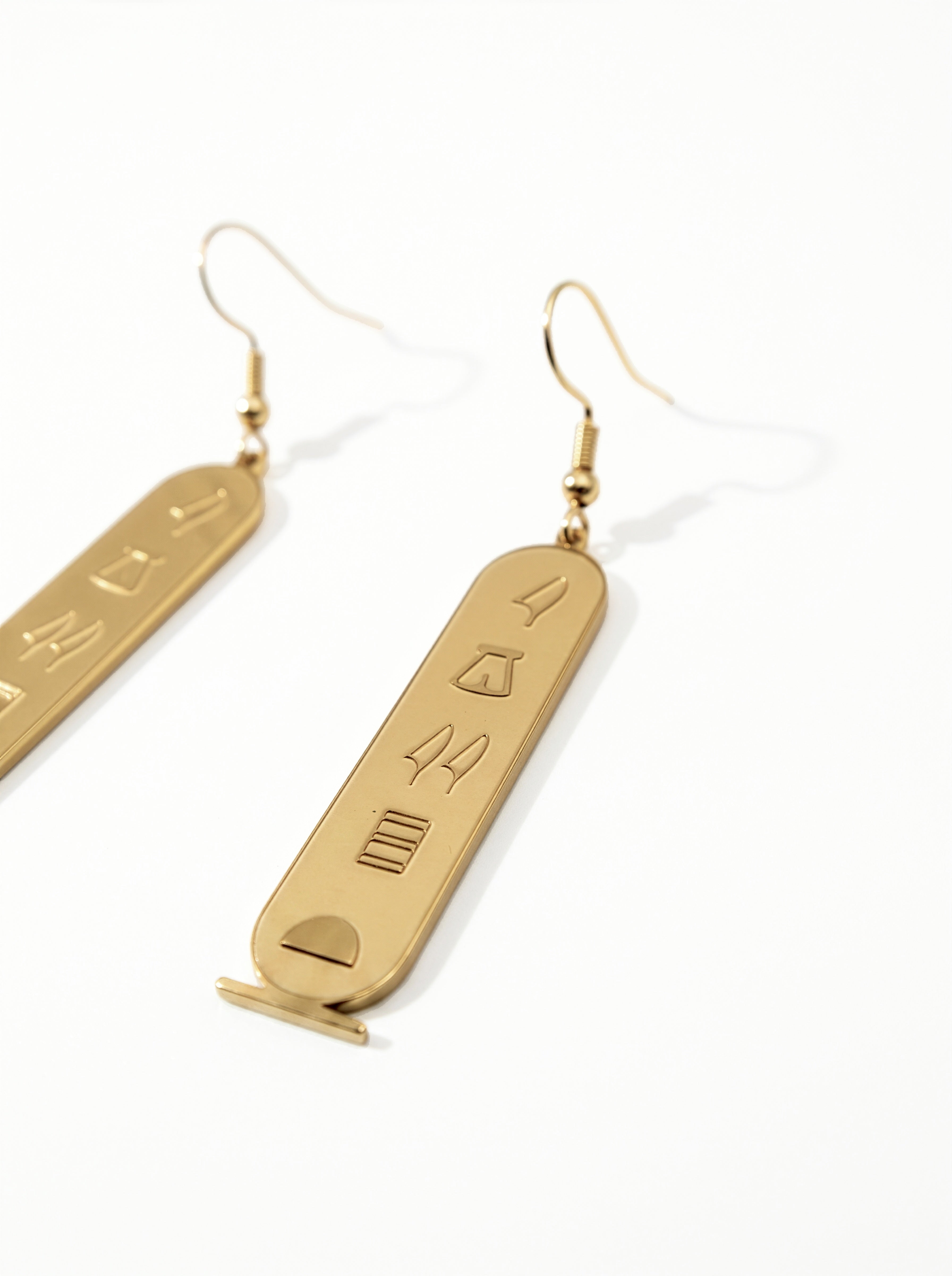 KIRO gold plated stainless steel drop earrings featuring oval cartouche pendants with engraved Egyptian hieroglyphs.