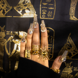 A hand wearing the Kiro Samer gold sunshine ring, paired with several other gold rings