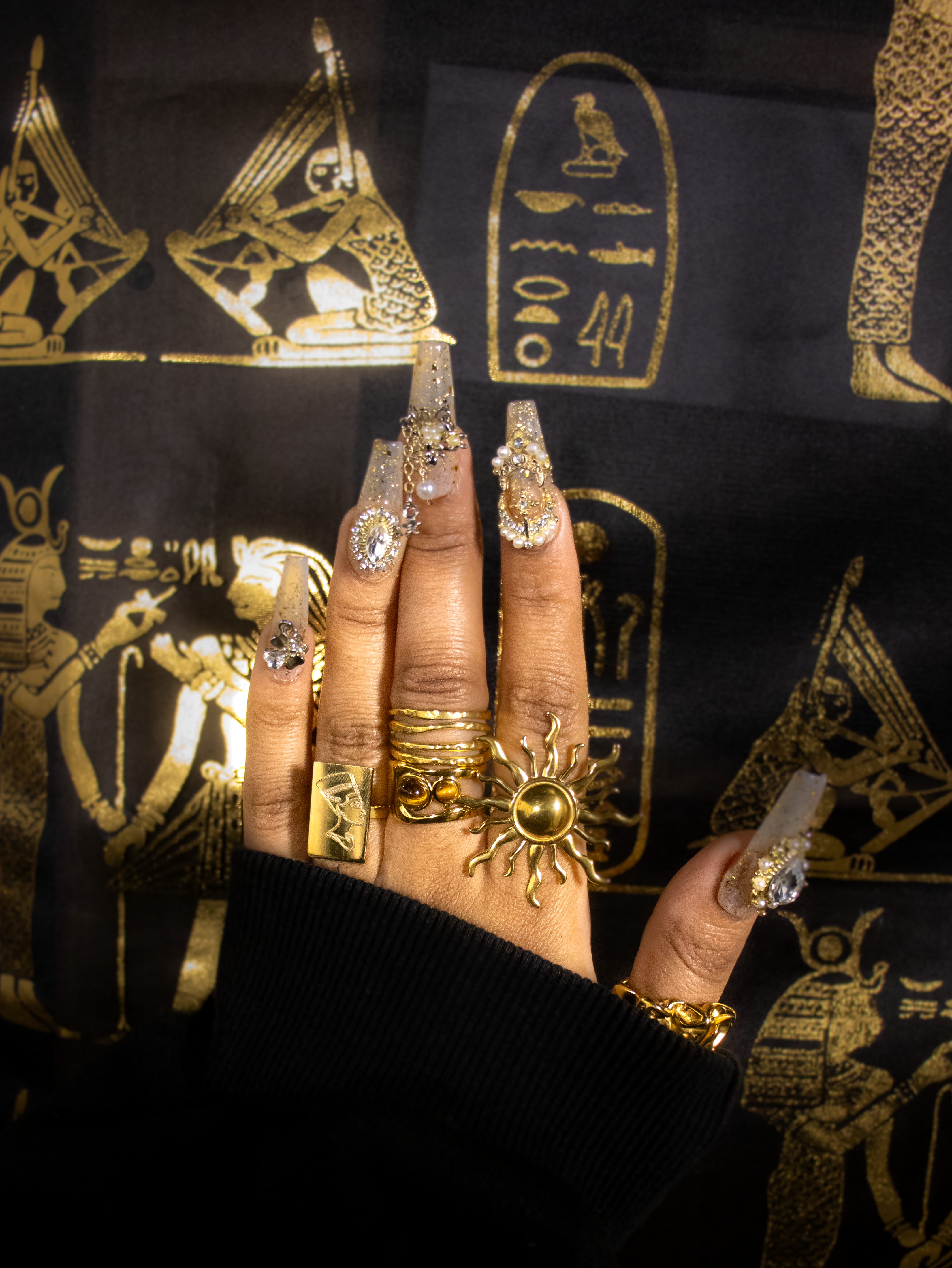 A hand wearing the Kiro Samer gold sunshine ring, paired with several other gold rings