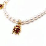 KIRO Scarab Pearl Necklace featuring ivory freshwater pearls and five gold-plated scarab charms with carnelian stones.