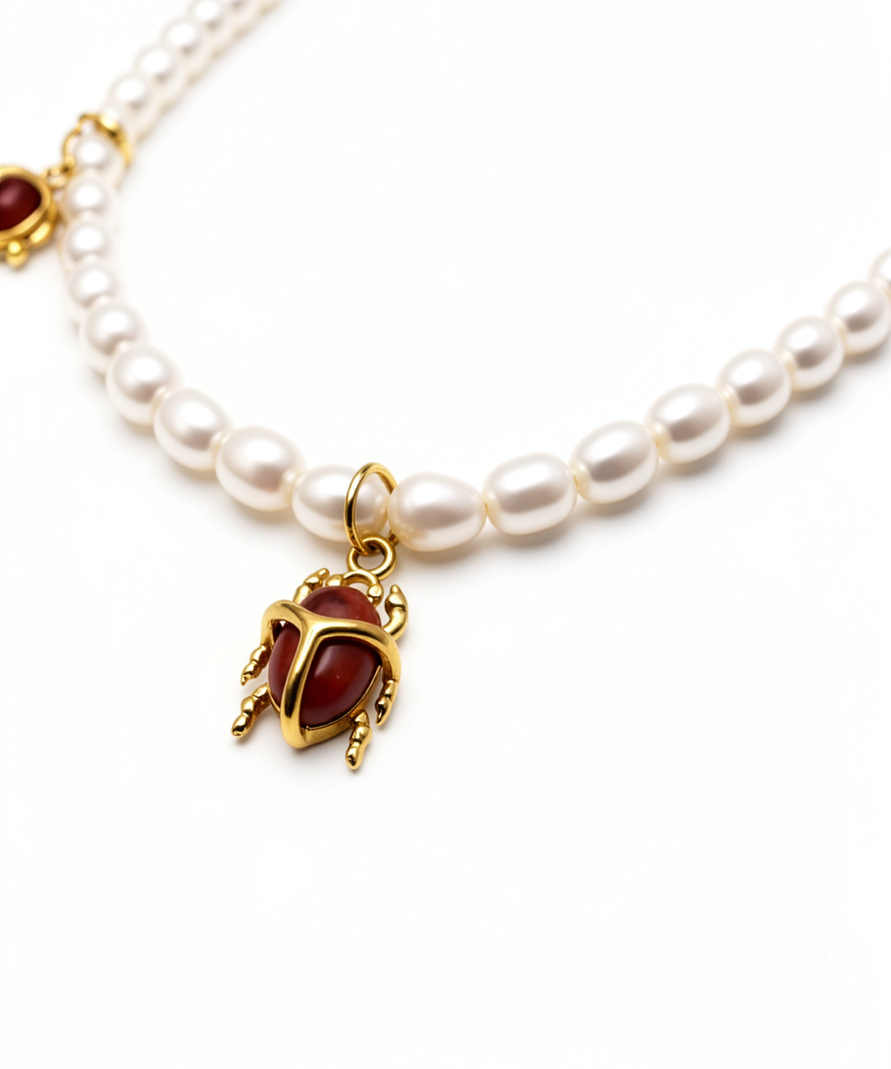 KIRO Scarab Pearl Necklace featuring ivory freshwater pearls and five gold-plated scarab charms with carnelian stones.