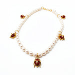 KIRO Scarab Pearl Necklace featuring ivory freshwater pearls and five 18k gold-plated scarab charms with carnelian stones.