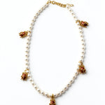 KIRO Scarab Pearl Necklace featuring ivory freshwater pearls and five gold-plated scarab charms with carnelian stones.