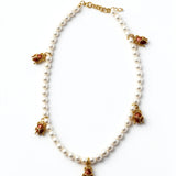 KIRO Scarab Pearl Necklace featuring ivory freshwater pearls and five gold-plated scarab charms with carnelian stones.