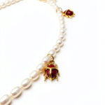 KIRO Scarab Pearl Necklace featuring ivory freshwater pearls and gold-plated scarab beetles with carnelian stones.