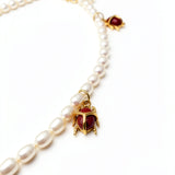 KIRO Scarab Pearl Necklace featuring ivory freshwater pearls and gold-plated scarab beetles with carnelian stones.