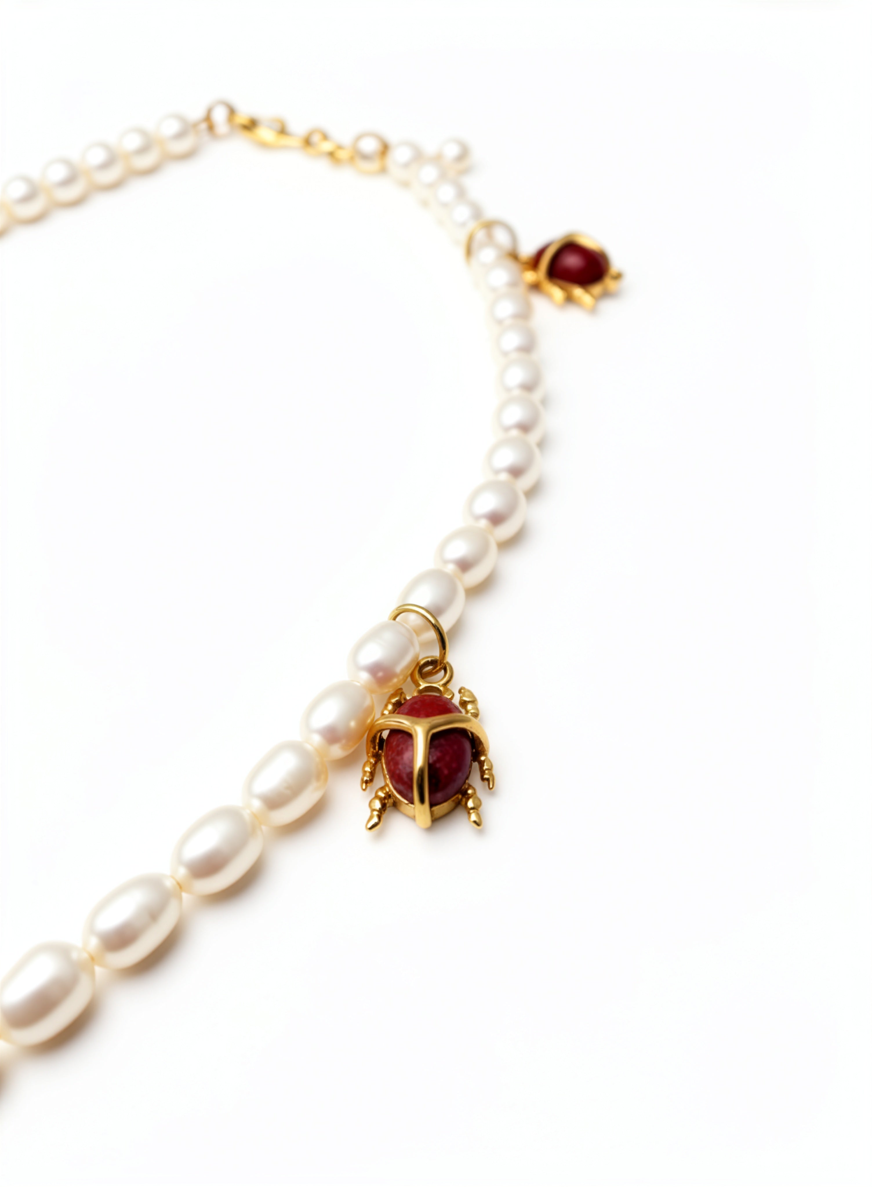 KIRO Scarab Pearl Necklace featuring ivory freshwater pearls and gold-plated scarab beetles with carnelian stones.
