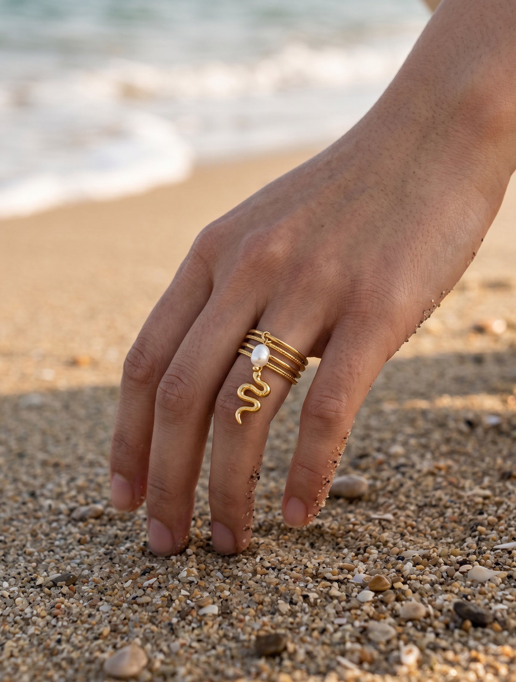 KIRO gold plated stackable ring with a dangling serpent charm and pearl accent. Resizeable.
