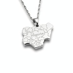 silver necklace of the map of Nigeria. "Nigeria" is written in the middle with all the cities engraved. the pendant hangs on a water wave chain.