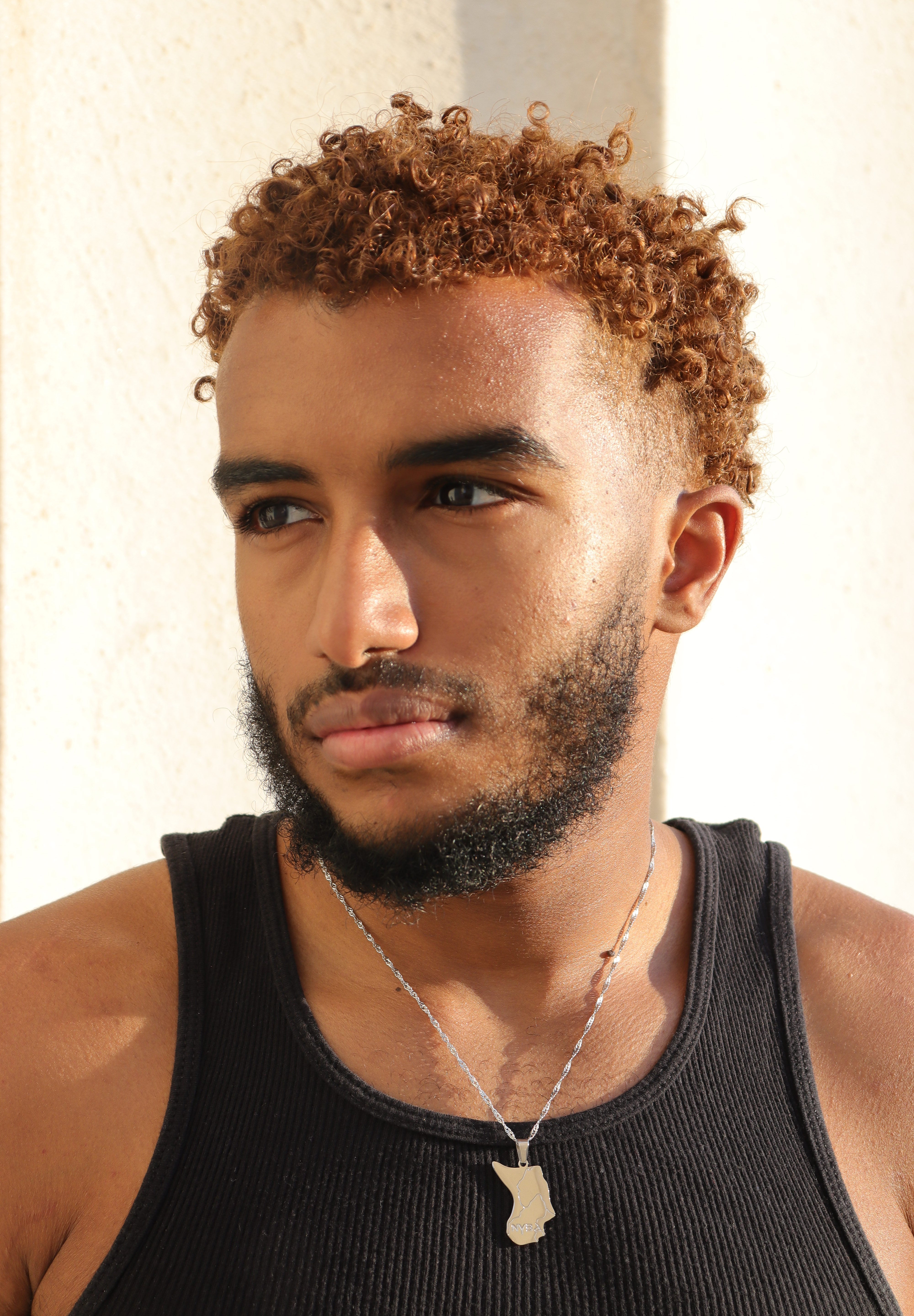 A man wearing a silver plated Nubia map necklace with a small engraved map pendant celebrating Nubian heritage by KIRO UK