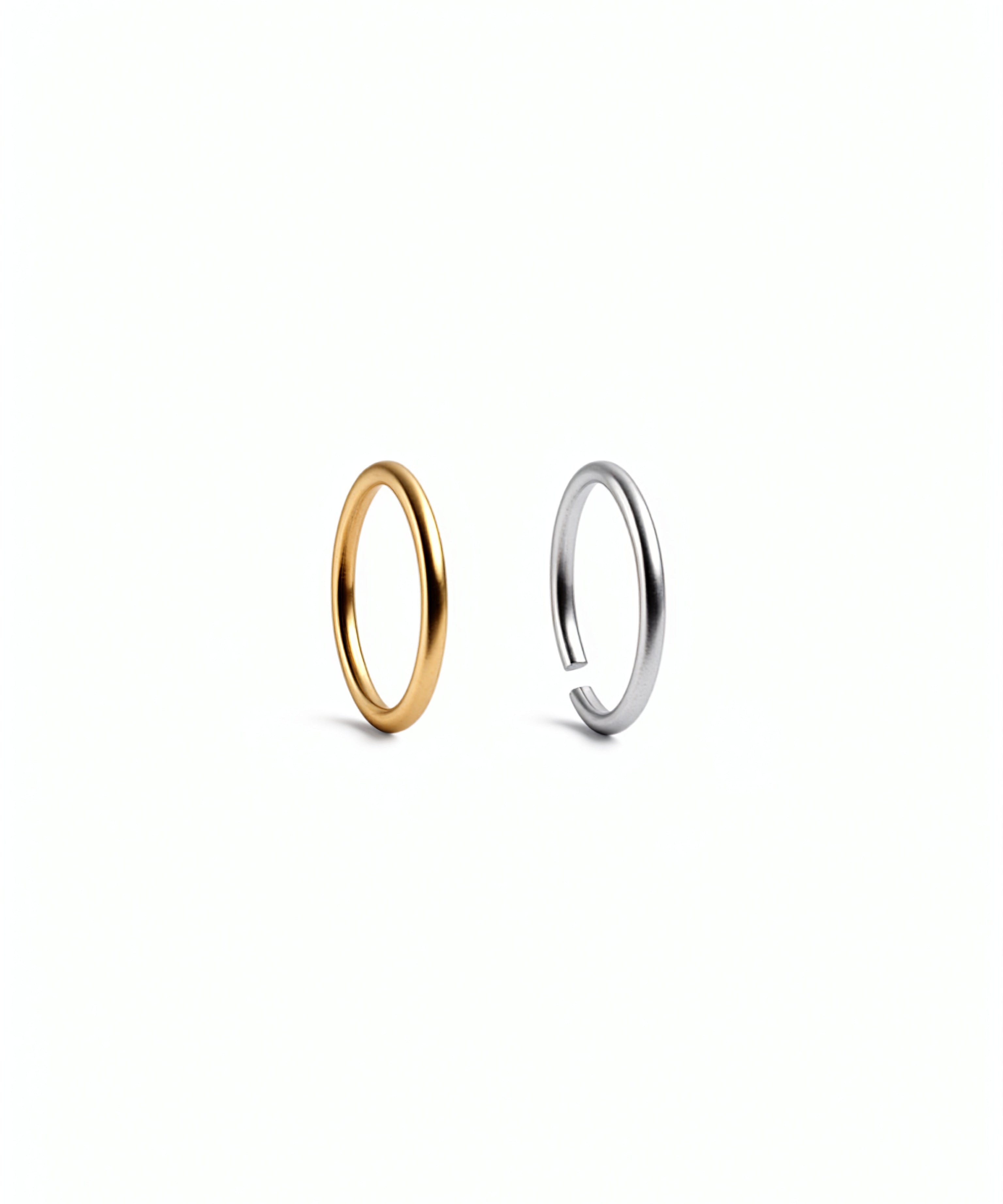 Pair of gold and silver tone hoop nose rings by KIRO UK shown on a white background with sleek open circular designs