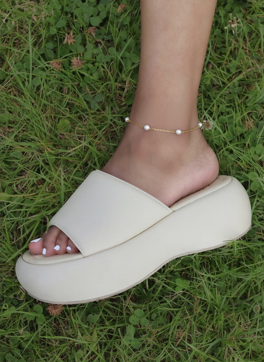 KIRO Lulu gold chain anklet with delicate freshwater pearls worn on an ankle above a cream platform slide sandal