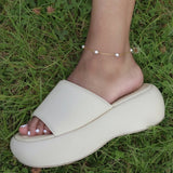 KIRO Lulu gold chain anklet with delicate freshwater pearls worn on an ankle above a cream platform slide sandal