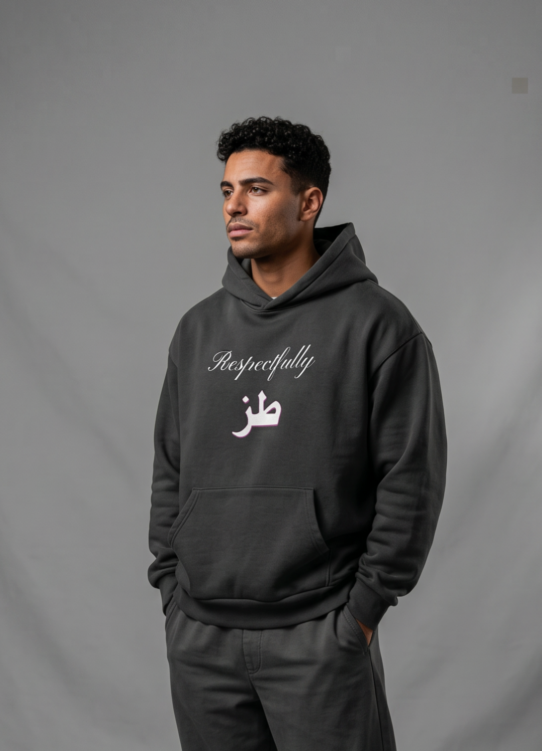Male model wearing a black oversized cotton hoodie with an extra large hood and Arabic lettering beneath Respectfully print from KIRO Clothing