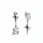 KIRO UK Earrings featuring silver plated star drop earrings with clear cubic zirconia accents and ornate sculpted lower charms on a white background