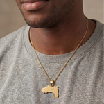 KIRO UK gold geometric Tigray map necklace worn over a gray shirt with a detailed pendant expressing cultural pride